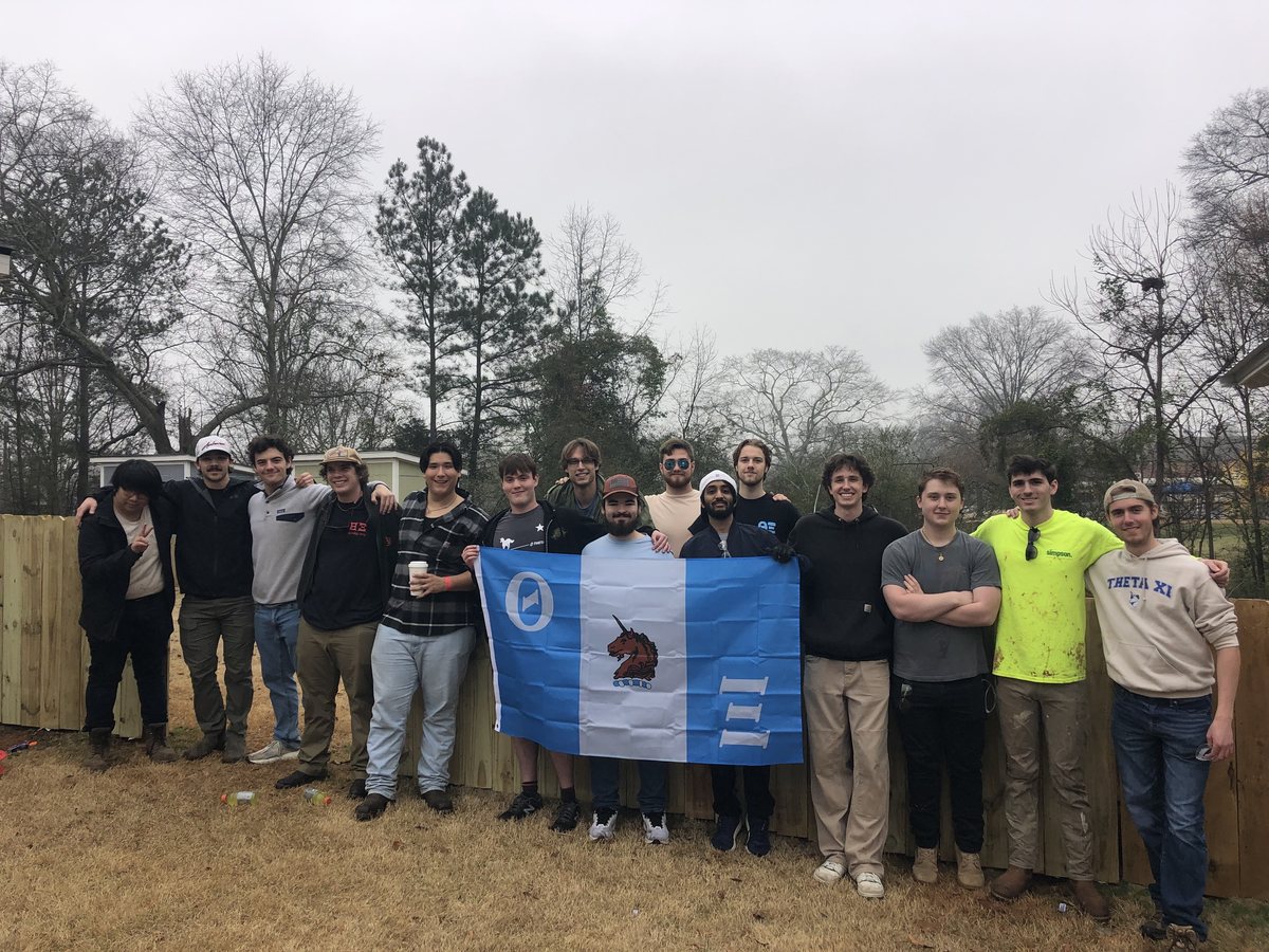 The brothers with the Theta Xi flag at a completed Habitat build
