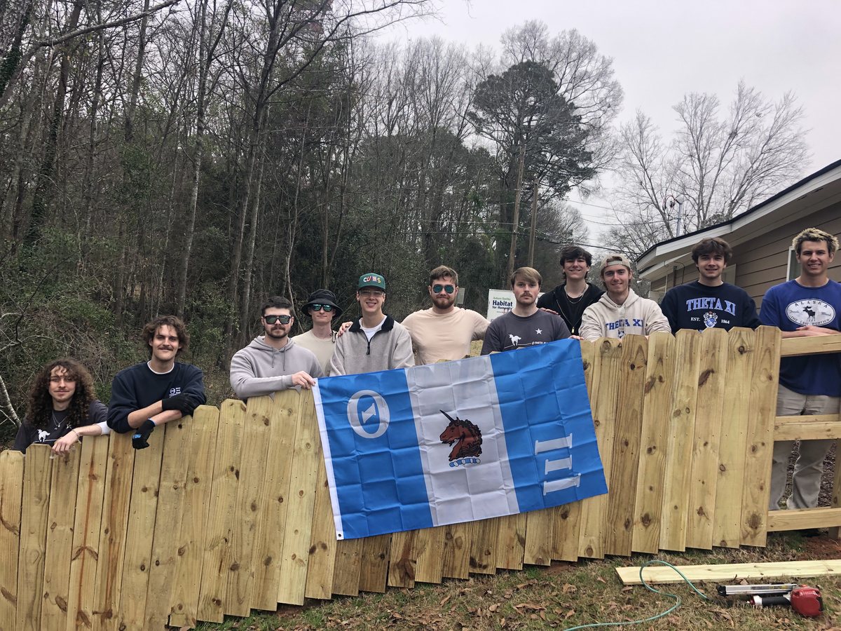 The chapter with the Theta Xi flag in front of a fence they built