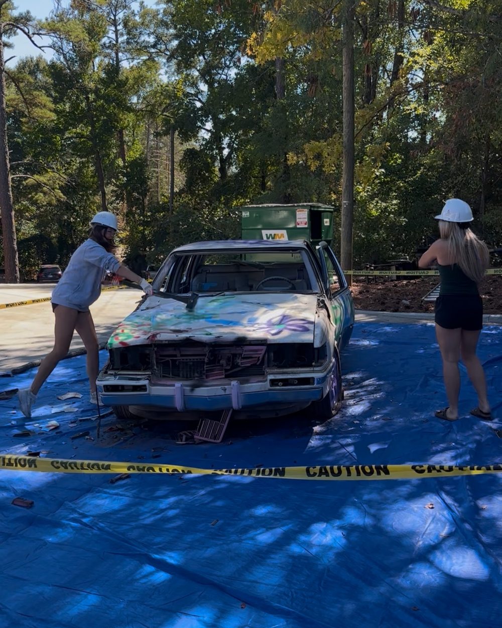 Students take swings at the Taxi Bash car on the front lawn